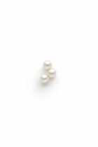 Boucle d'oreille grimpante James composée de trois perles de culture blanches en grappe sur fond blanc.